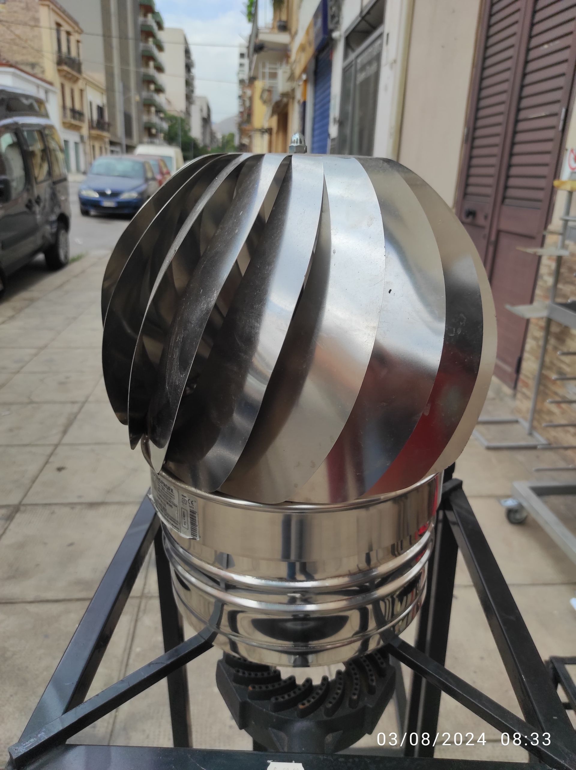 Un camino rotante in acciaio inossidabile lucido, esposto all'aperto in una giornata di sole.