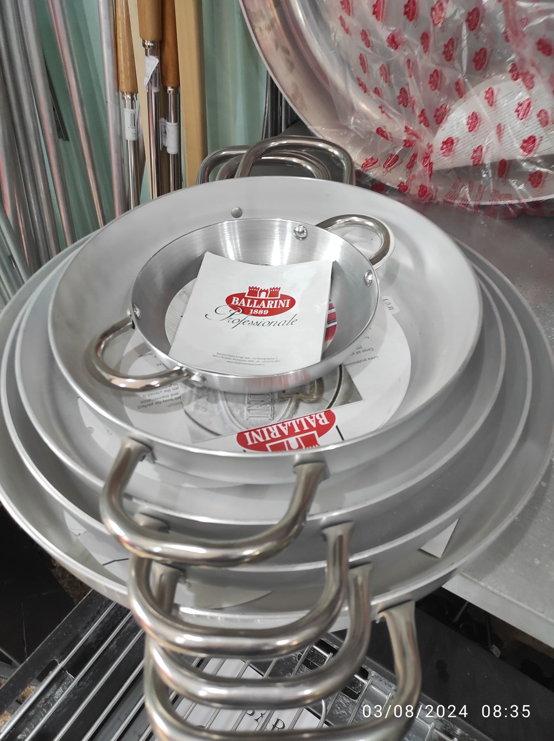 Pila di padelle in alluminio con manici, alcune con inserti in carta.