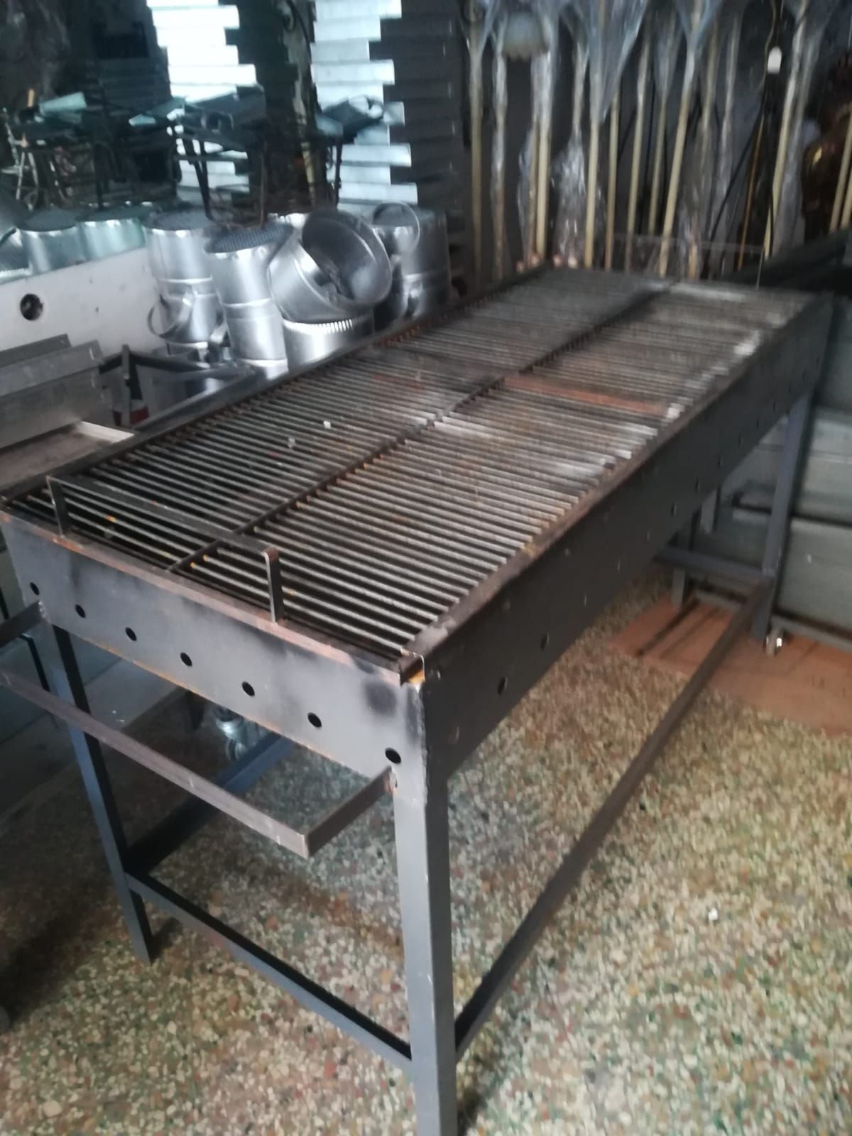 Ampia postazione per grigliare all'aperto, nera, con griglia in metallo.