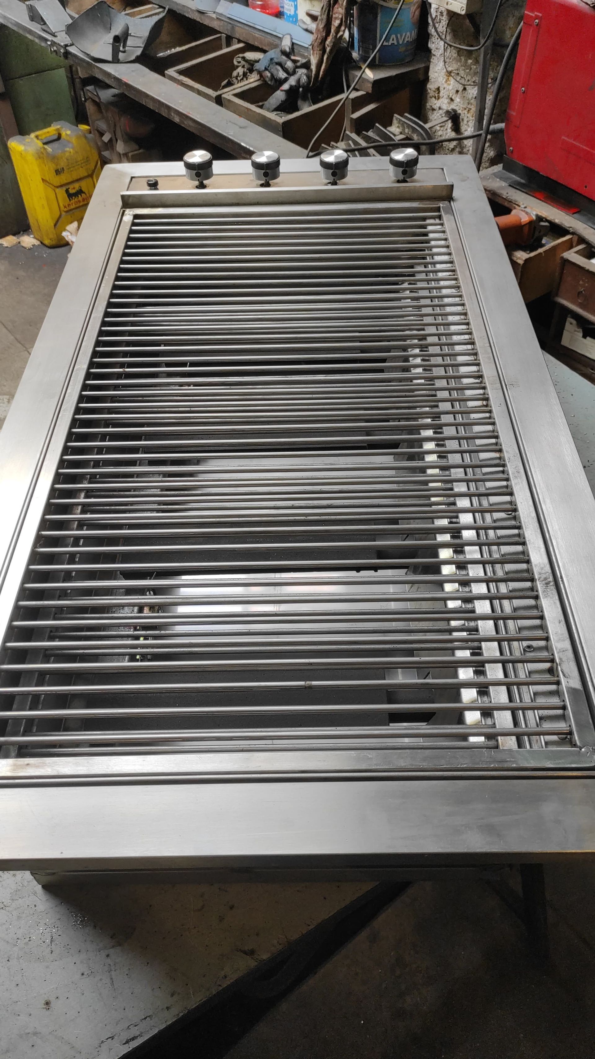 Griglia da incasso in acciaio inox con tre manopole. Le griglie scorrono orizzontalmente, in un ambiente da laboratorio.