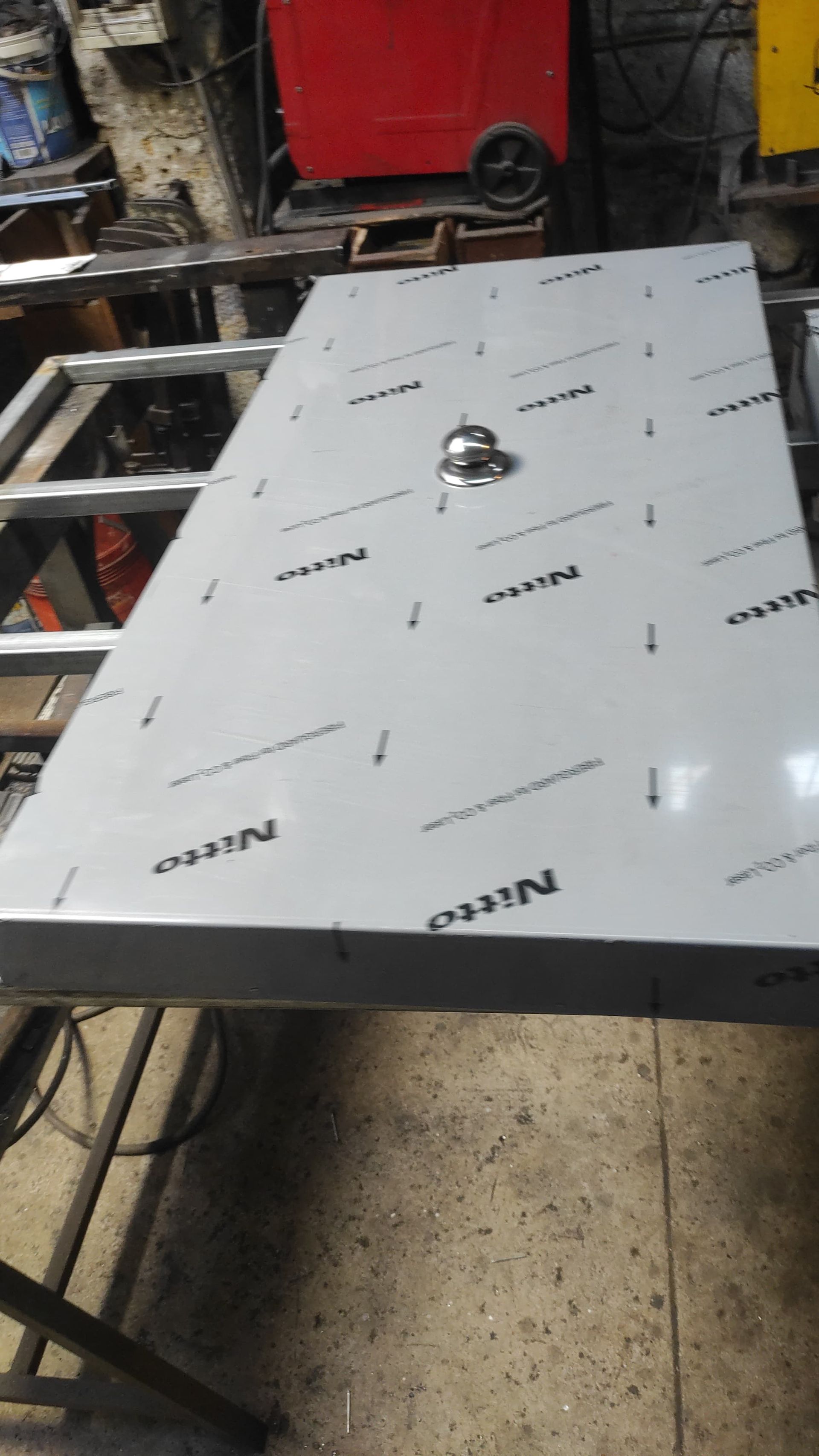 Lamiera di acciaio inossidabile con maniglia, loghi Nitro, su un telaio metallico in un'officina.