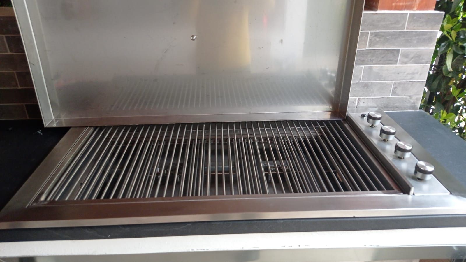 Griglia da esterno aperta in acciaio inox con griglie e manopole di controllo.