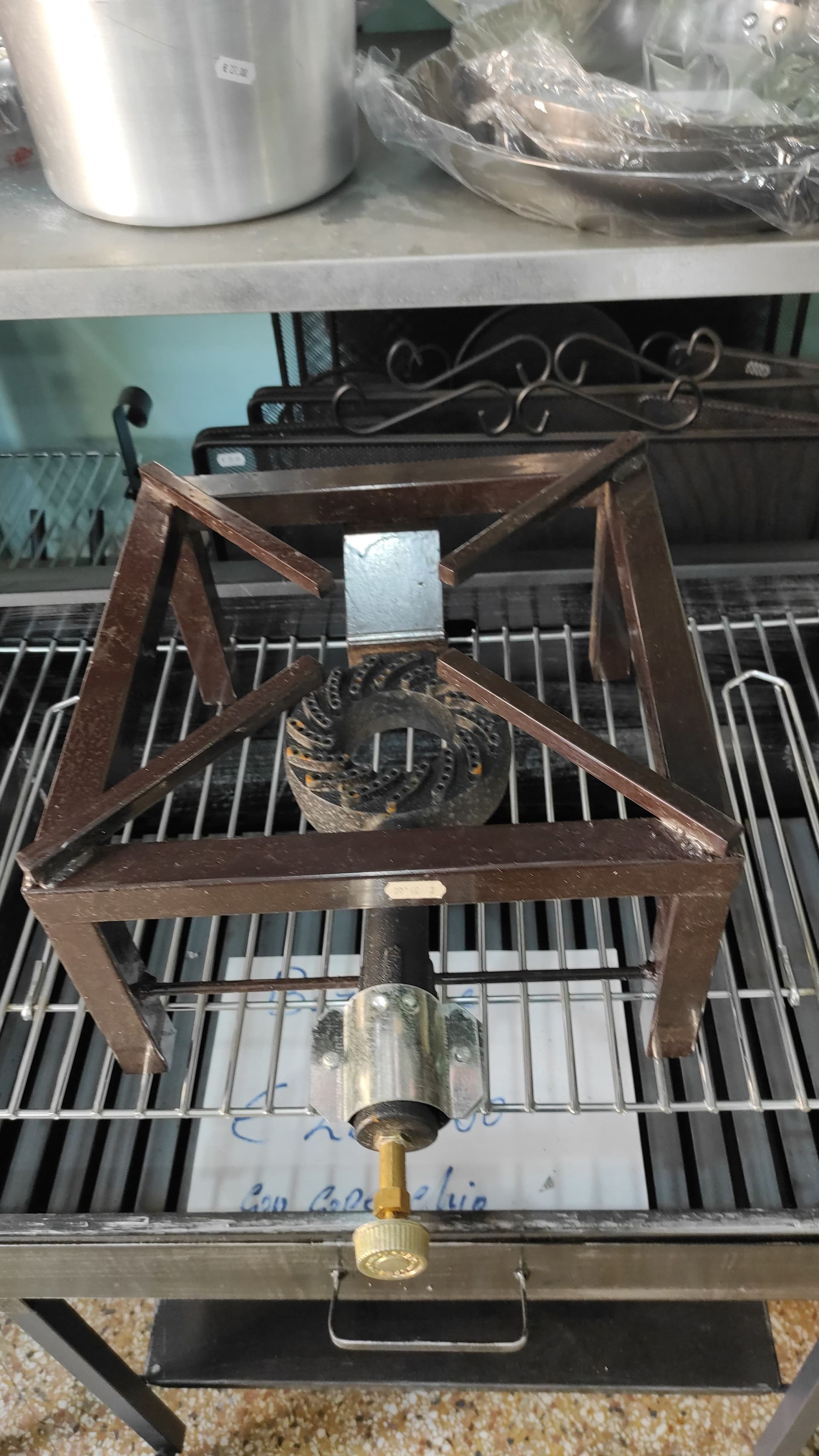 Bruciatore a gas con telaio metallico quadrato, posizionato su una griglia metallica.