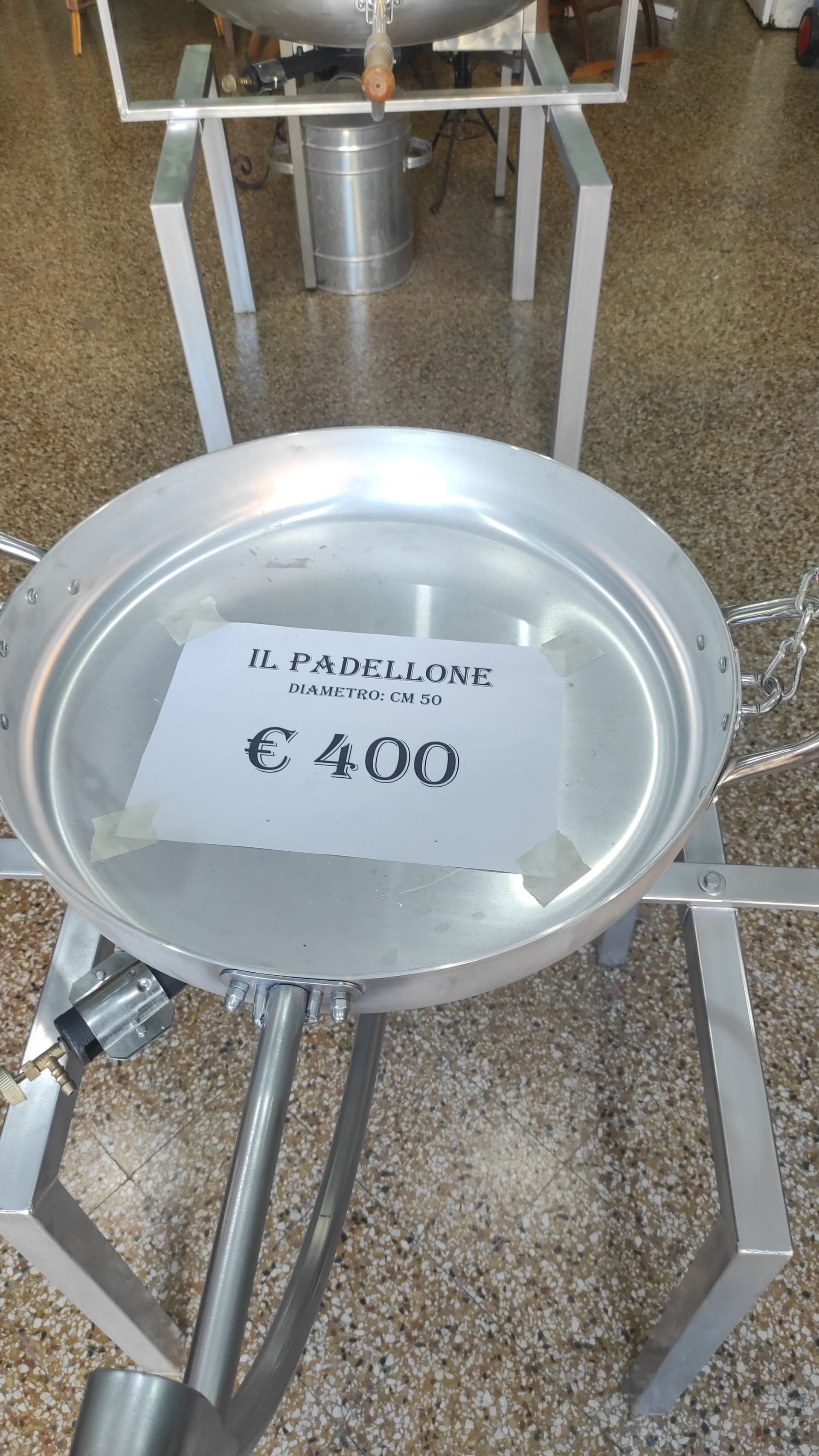 Grande padella di metallo con etichetta del prezzo (400 €) su supporto di metallo.