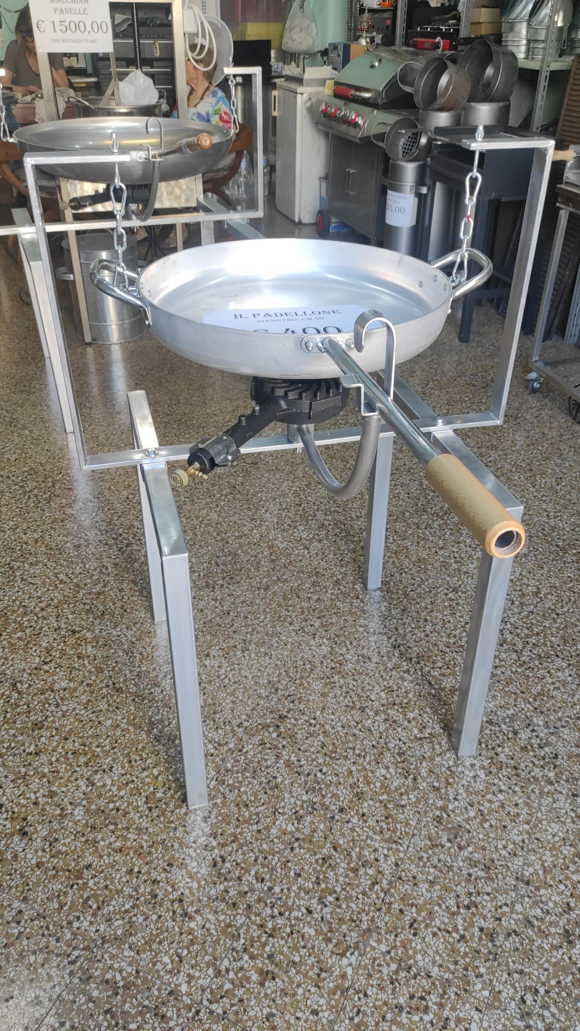 Attrezzatura per cucinare con una grande padella di metallo sospesa su un fornello a propano, su un supporto di metallo.