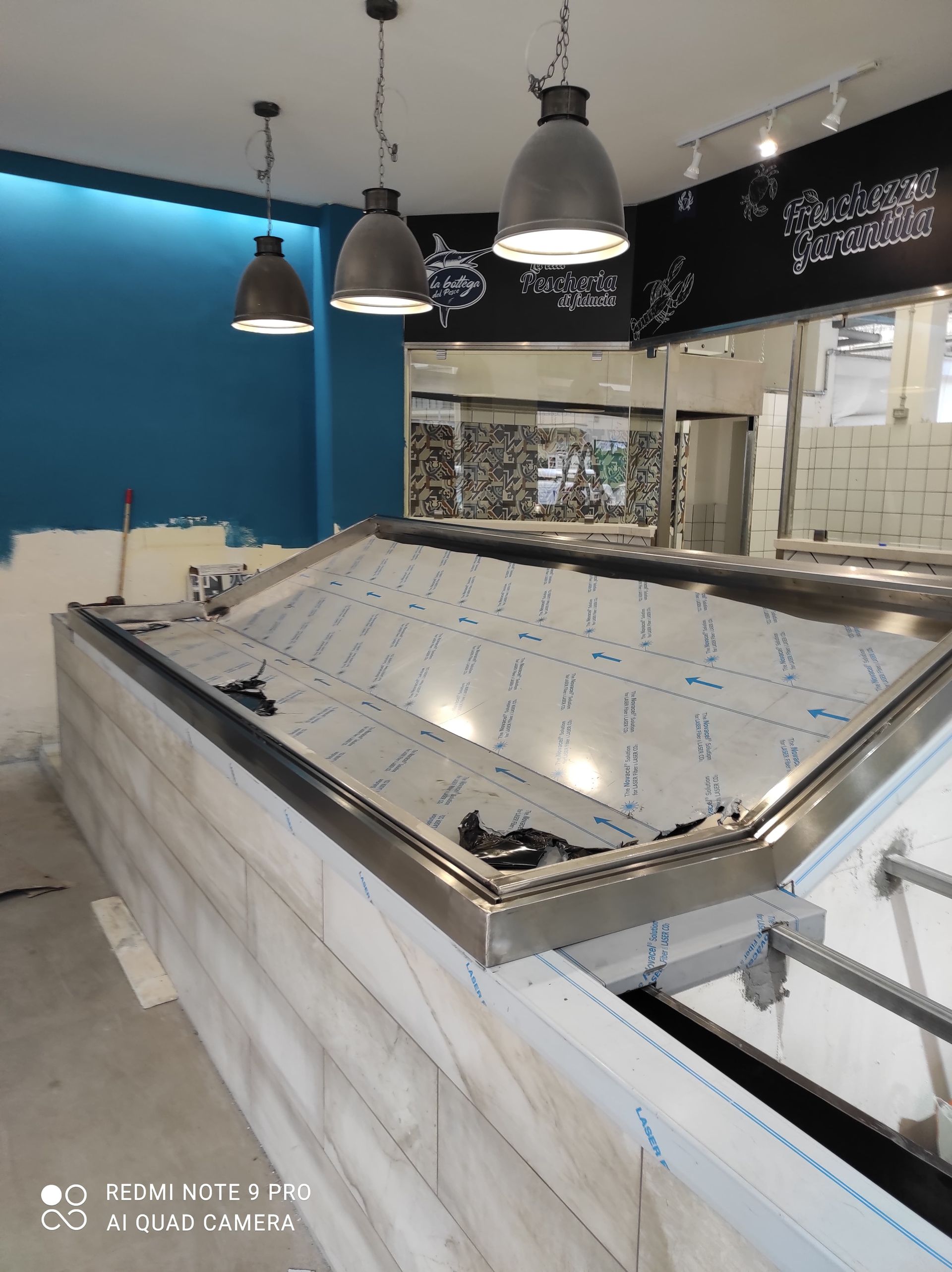 Vetrina vuota per pesci in un negozio in costruzione, nei toni del grigio e del blu.