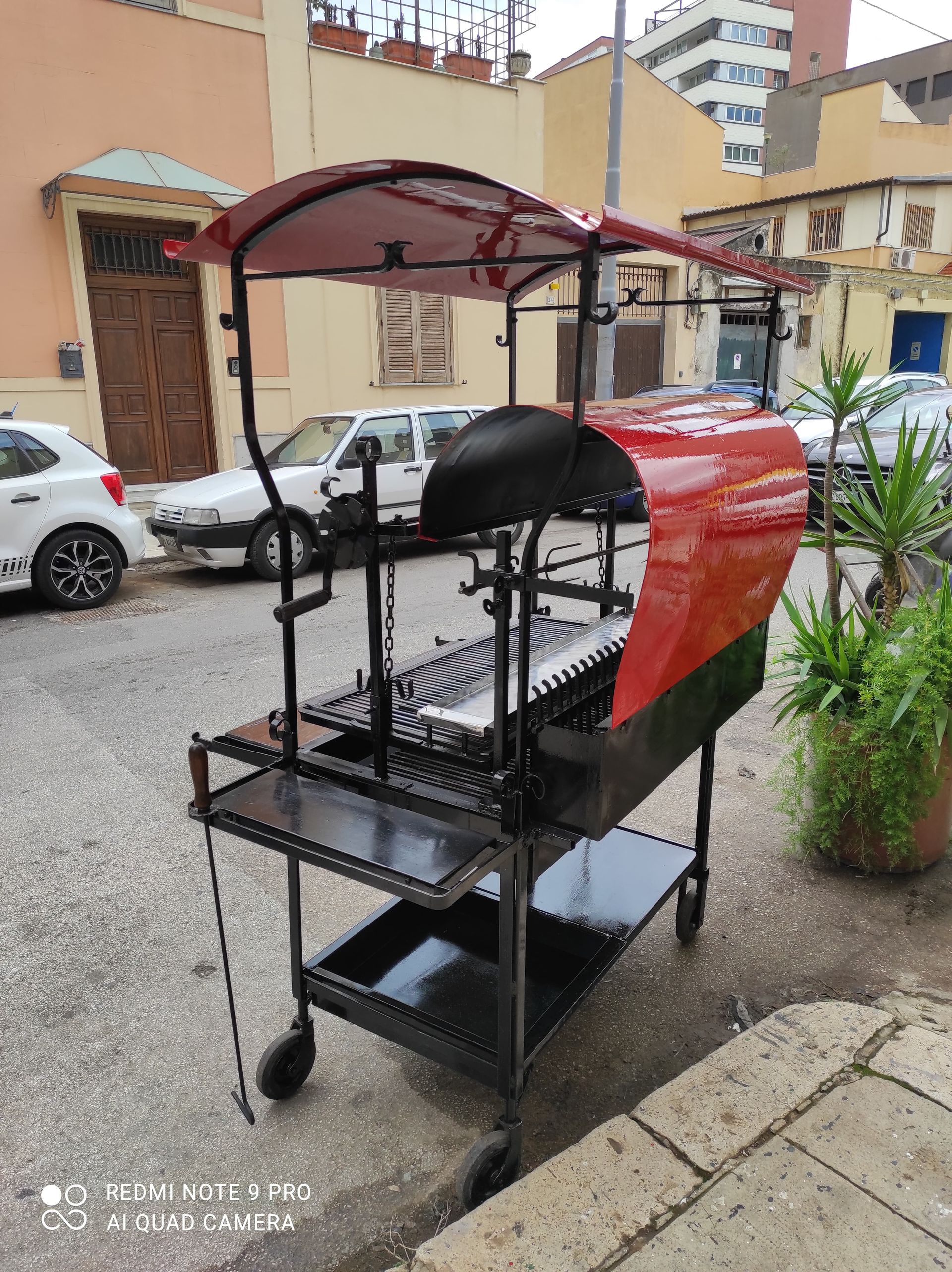 Carretto rosso e nero con tettoia su una strada cittadina.