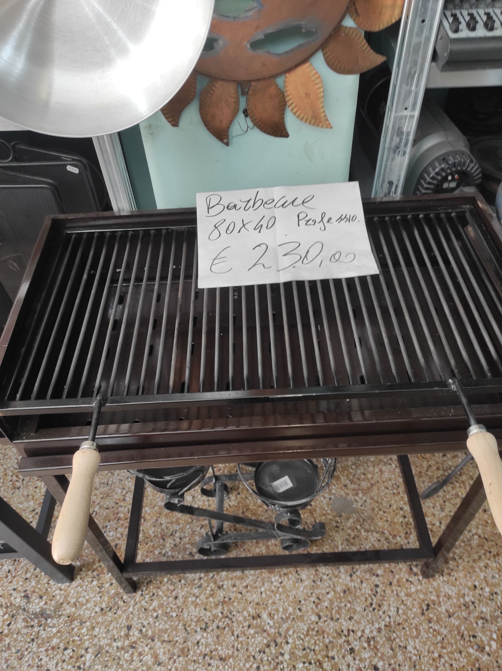 Griglia con cartellino del prezzo: metallo scuro, manici in legno, su supporto, per interni.