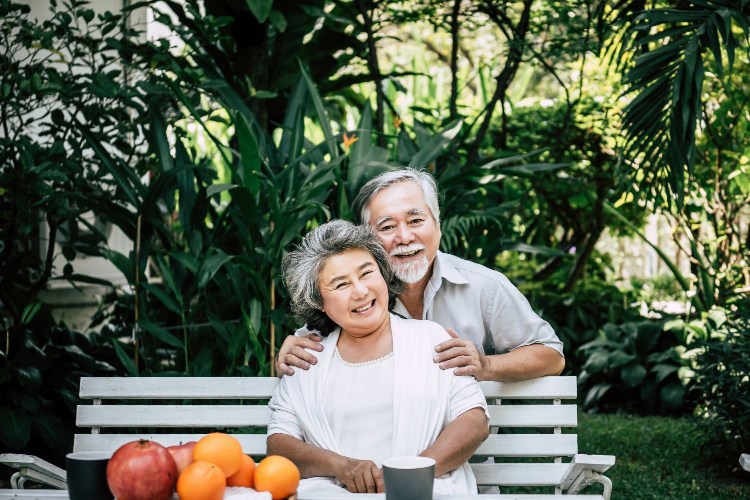 An elderly couple is sitting on a bench in a park.
