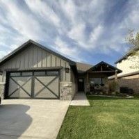 A house with a large garage door and a large lawn in front of it.