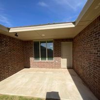 A brick house with a patio and a large window.