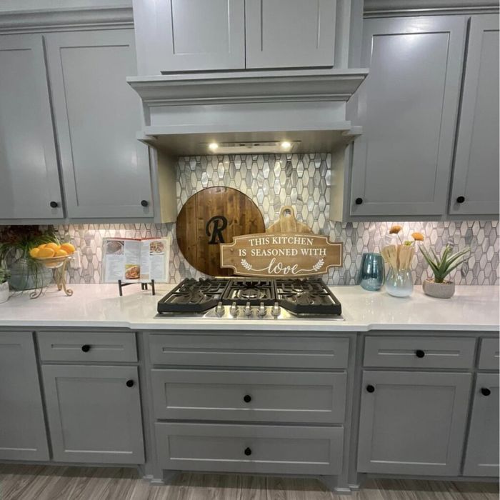A kitchen with gray cabinets and a stove top oven.