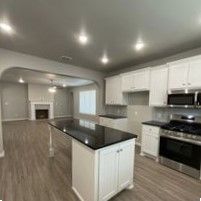 A kitchen with white cabinets , stainless steel appliances , a large island , and a fireplace.