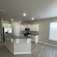 A kitchen with granite counter tops and stainless steel appliances in a new home.