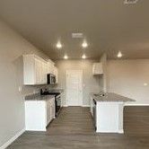 An empty kitchen with white cabinets and stainless steel appliances.