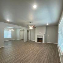 An empty living room with a fireplace and ceiling fan.