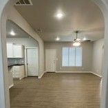 An empty living room with hardwood floors and a ceiling fan.