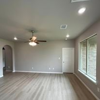 An empty living room with hardwood floors and a ceiling fan.