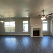 An empty living room with a fireplace and ceiling fan.