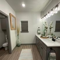 A bathroom with two sinks , a toilet , and a large mirror.