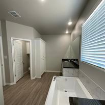 A bathroom with a tub , sink , mirror and window.
