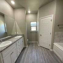 A bathroom with two sinks , a tub and a mirror.