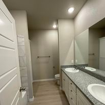 A bathroom with two sinks , a toilet , and a large mirror.