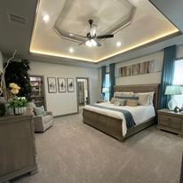 A bedroom with a bed , dresser , nightstand , chair and ceiling fan.