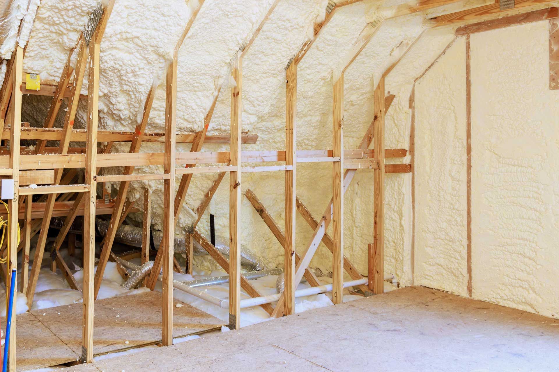 Attic interior with wooden framing and spray foam insulation in beige.