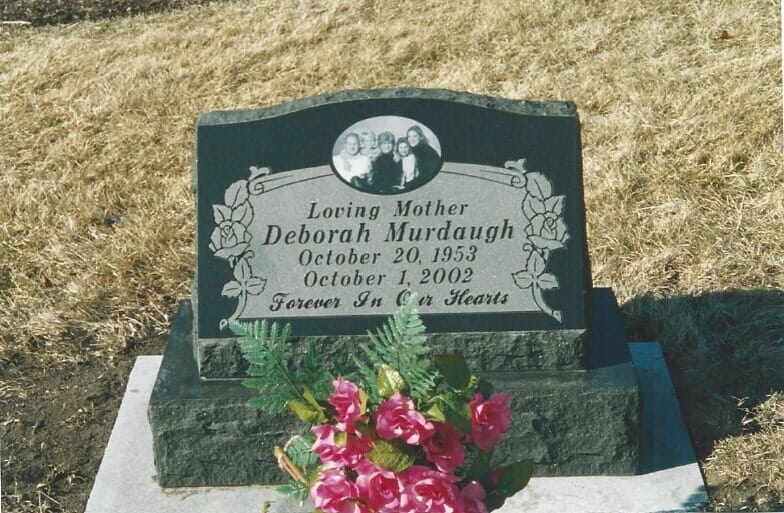 Headstone for Deborah Murdaugh, born 1953, died 2002. Includes photo, flowers.