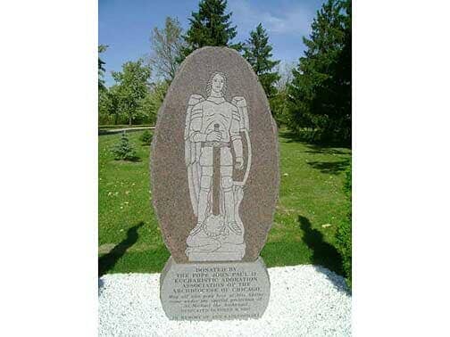 Granite memorial of a soldier, with inscription, in a park.