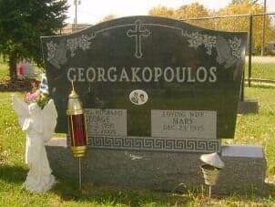 Headstone of Georgakopoulos with a cross, angel statue, and candleholder.