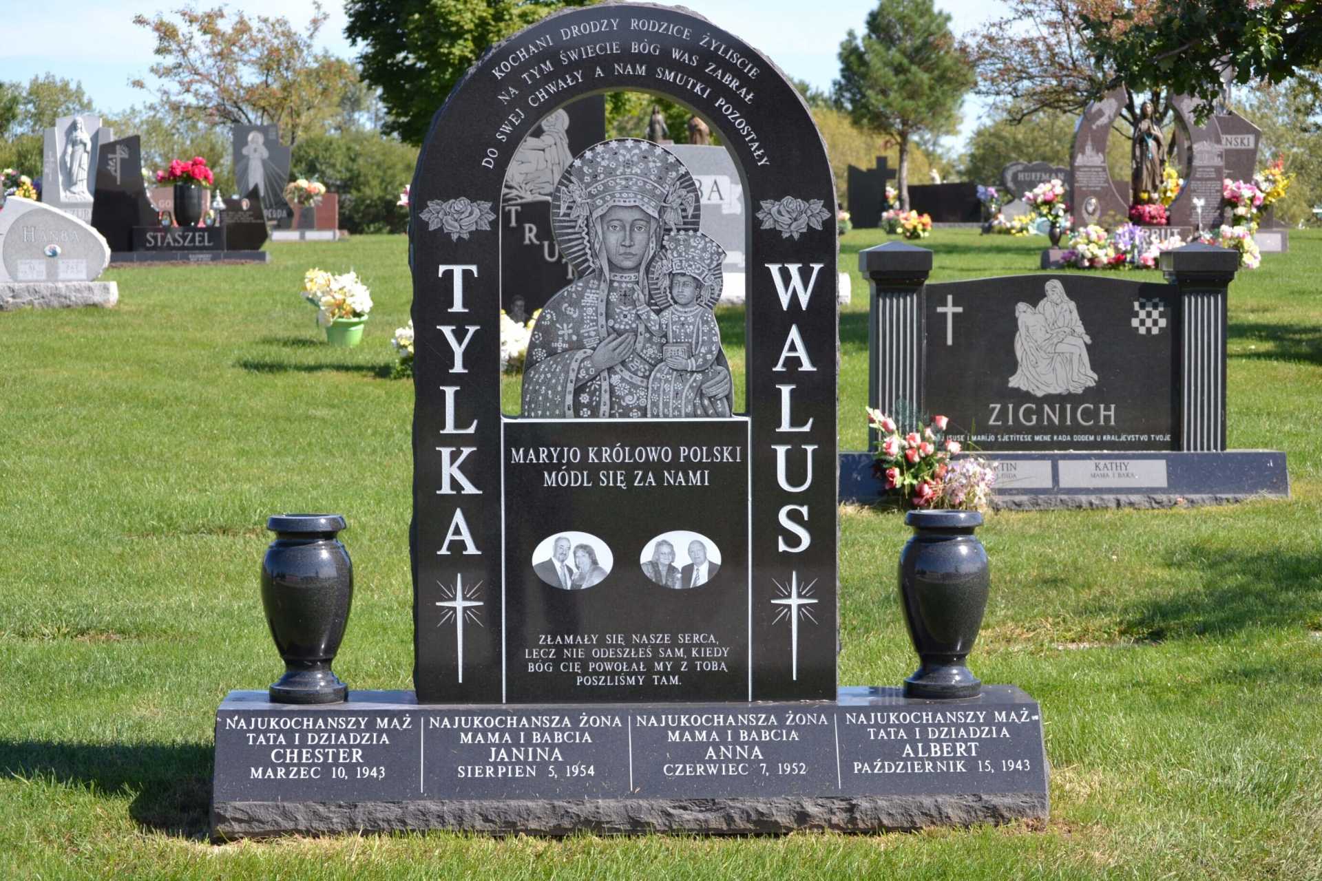 Black headstone with arch, carving of a religious figure, names Tylka Walus, set in a cemetery.