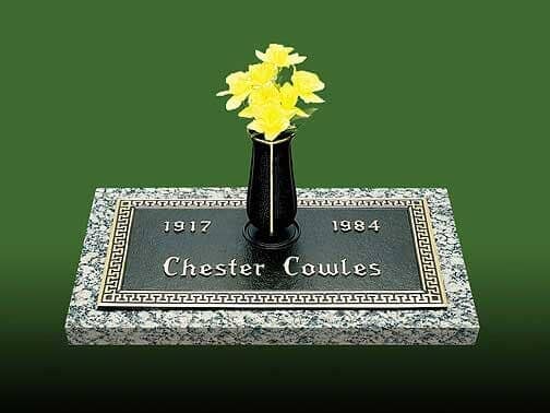 Headstone with a black vase of yellow flowers; the inscription reads: