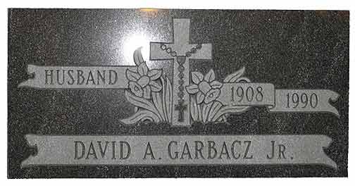 Gravestone of David A. Garbacz Jr. with cross, flowers, banner reading 