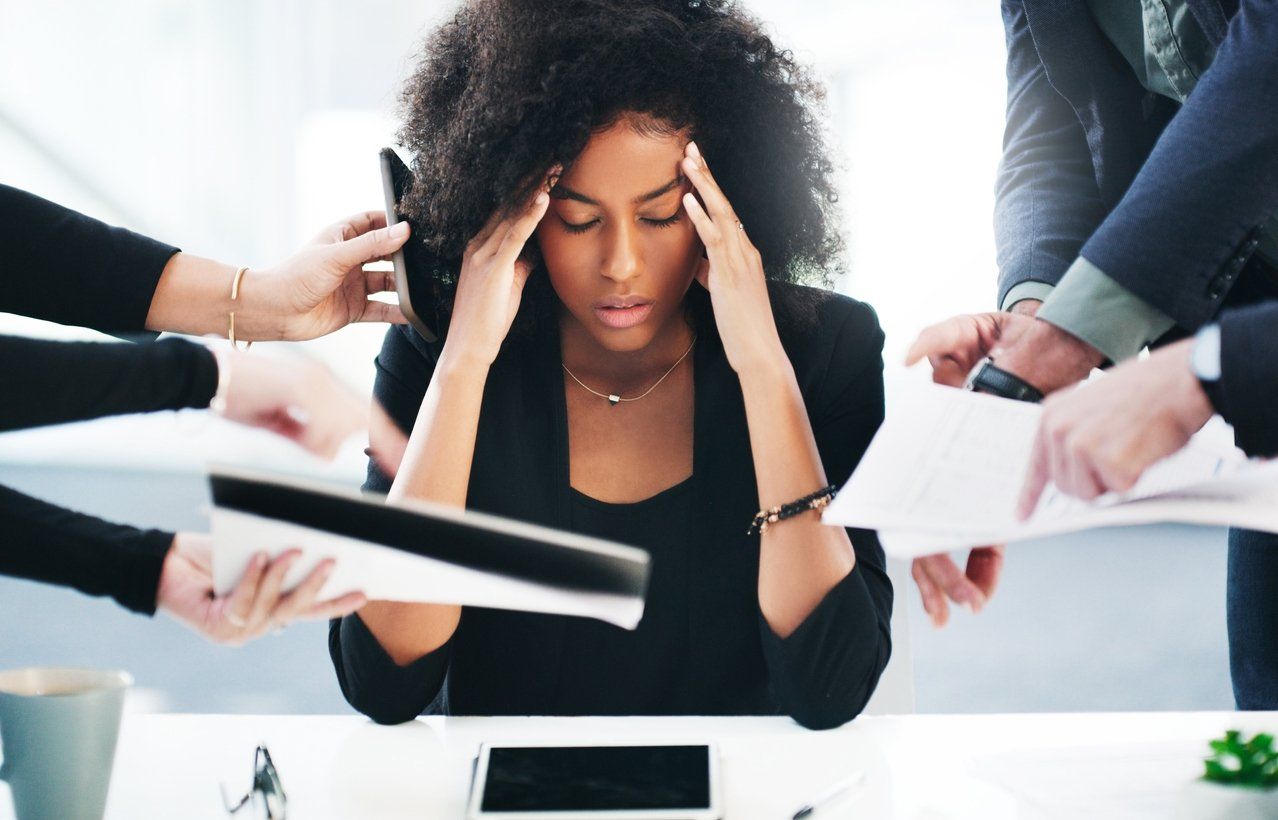 Female professional in an office experiencing job burnout - showing stress while being overwhelmed with tasks.