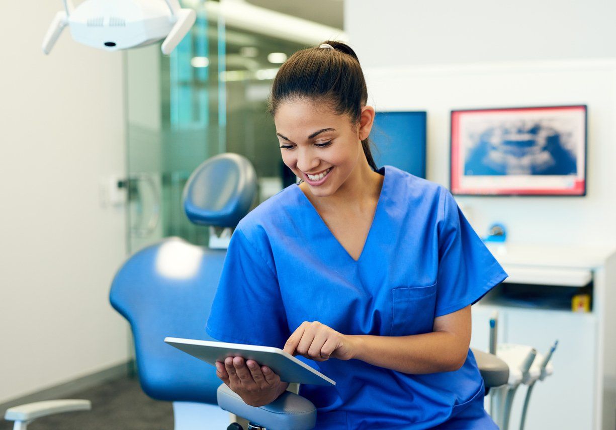 Female dentist using a tablet device to reach more customers for her dental business.