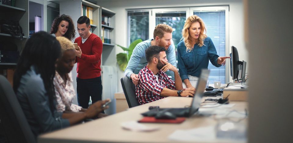 Team of professionals in an office using different devices to plan and discuss about their business' brand visibility.