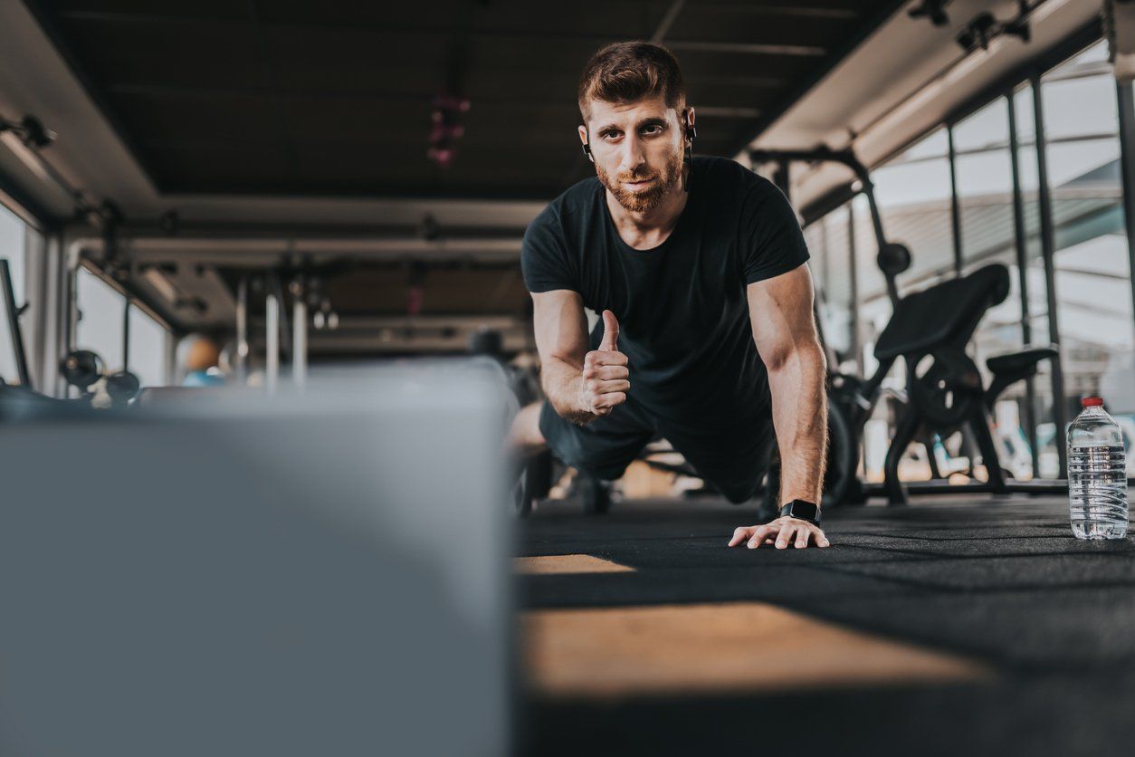 Male personal trainer in a fitness gym creating online workout videos.