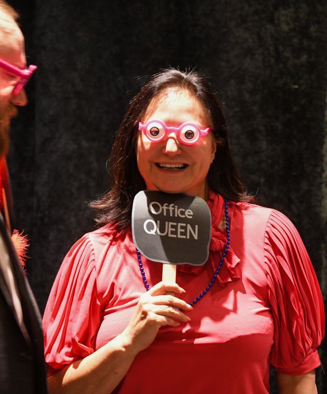A woman holding a sign that says office queen