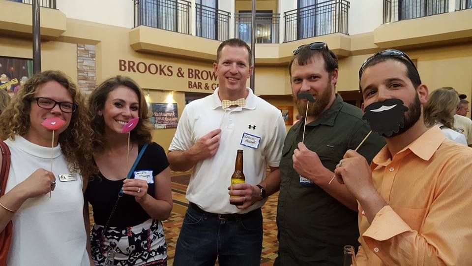 A group of people are posing for a picture in front of a building that says brooks & brown