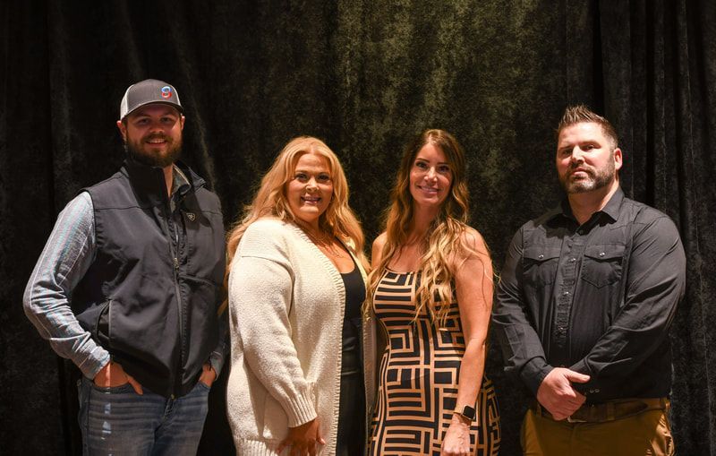 A group of people are standing next to each other in front of a black curtain.
