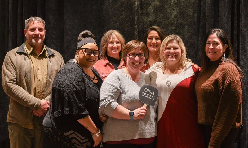 A group of people are posing for a picture in front of a black curtain.