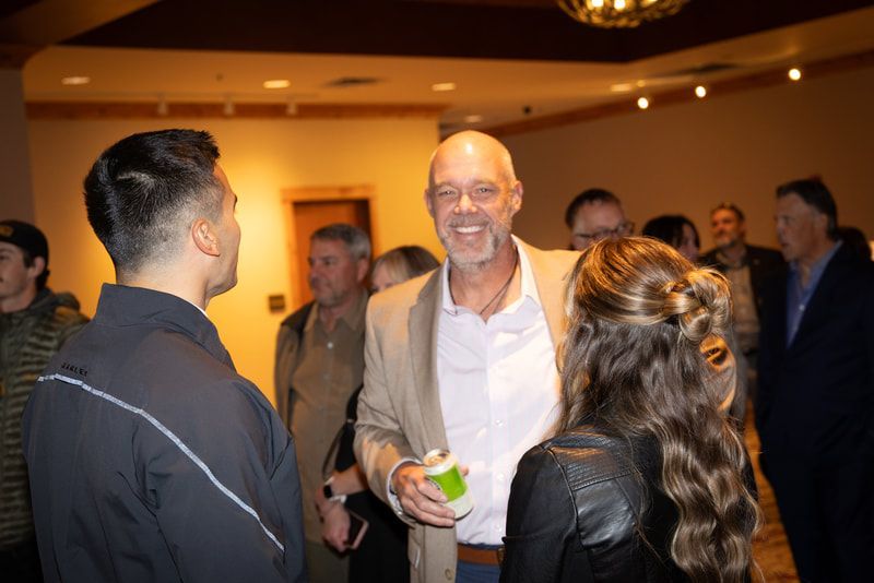 A group of people are standing in a room talking to each other.