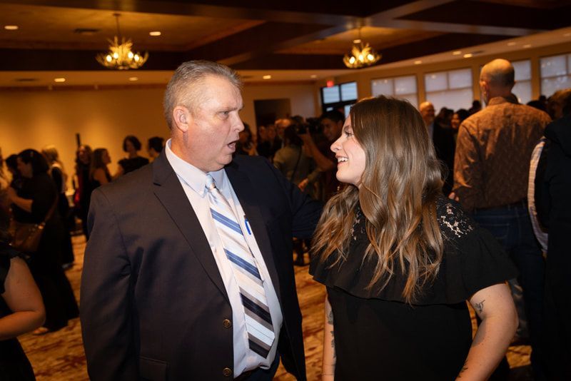 A man in a suit and tie is talking to a woman in a black dress.