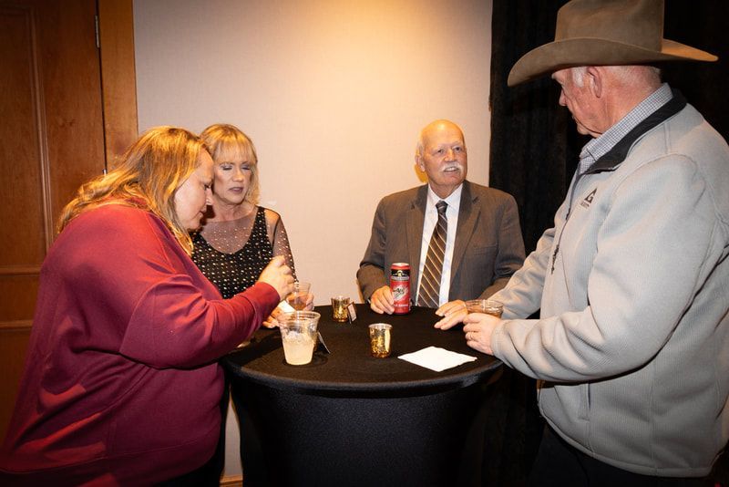 A group of people are standing around a table talking to each other.
