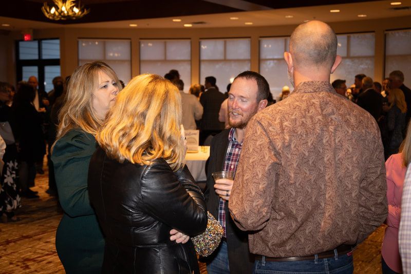 A group of people are standing in a room talking to each other.