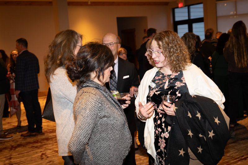 A group of people are standing in a room talking to each other.