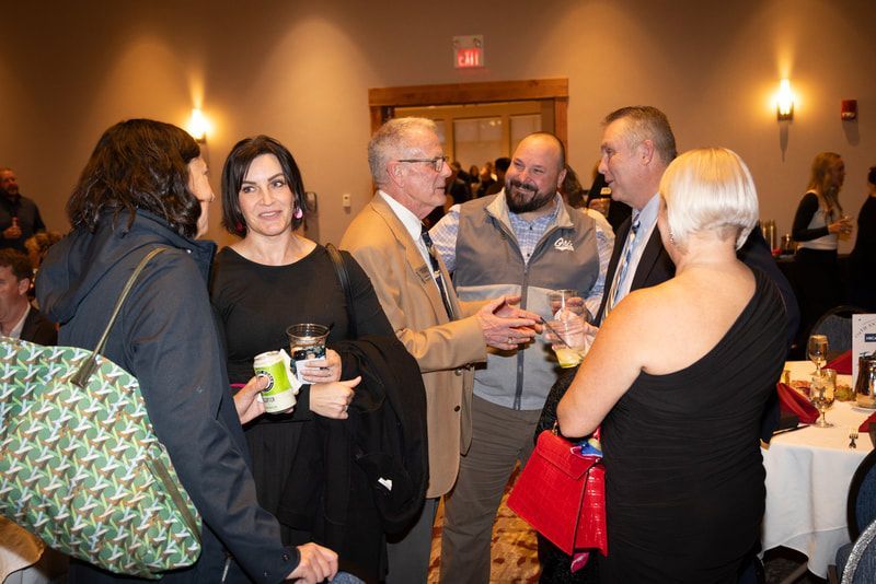 A group of people are standing in a room talking to each other.