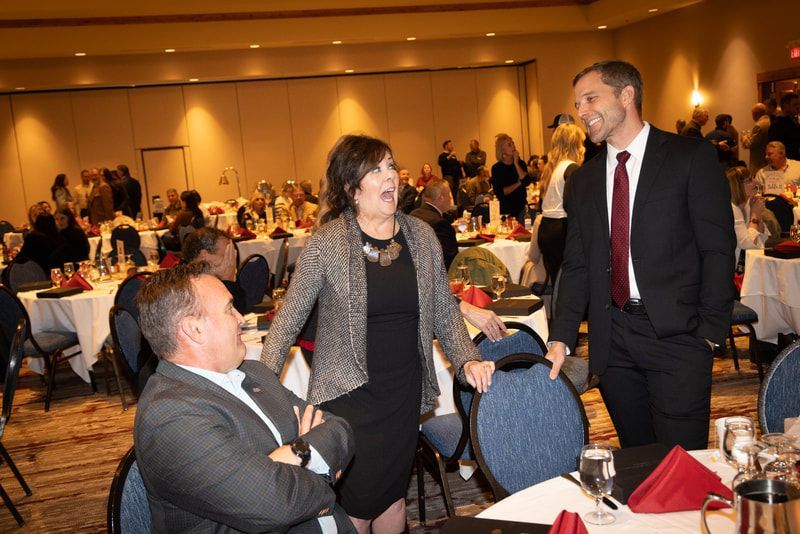 A group of people are sitting at tables in a large room talking to each other.